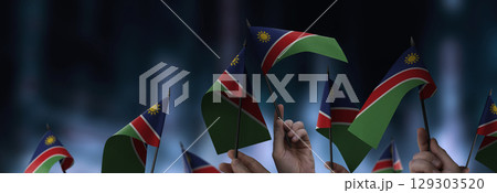 Namibia flags in their hands on a blurred urban background Namibia flags in their hands on a blurred urban background 129303520