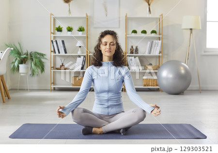 Yogi sporty woman practicing yoga doing relaxing exercise, meditating in Half Lotus pose with mudra 129303521
