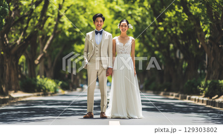 新郎と新婦が並木道で優雅に微笑む結婚記念写真 129303802