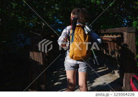 Hiker With Yellow Backpack Crossing a Wooden Bridge in a Forest Hiker With Yellow Backpack Crossing a Wooden Bridge in a Forest 129304226
