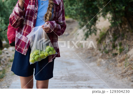 Young Woman Holding a Bag of Freshly Picked Green Figs on a Rural Pathway Young Woman Holding a Bag of Freshly Picked Green Figs on a Rural Pathway 129304230