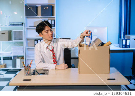Asian male professional packing office belongings in a box, representing themes of resignation, new job, 129304631
