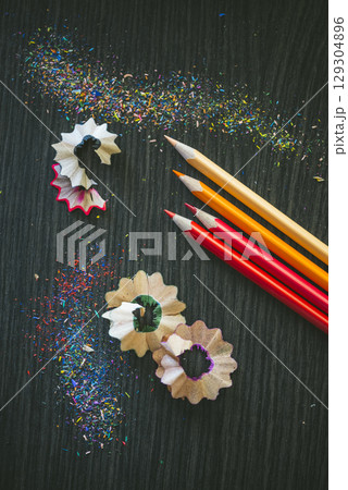 Colorful Pencil Shavings and Sharpened Pencils on Dark Surface 129304896