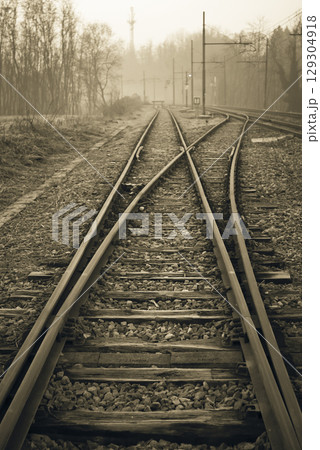 Sepia Toned Railway Tracks Splitting in Misty Landscape 129304918