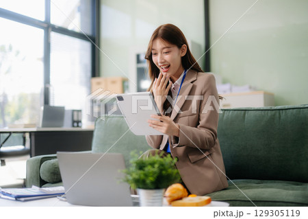 Young Asian working on laptops and tablets in a stylish office. Perfect for creativity, remote work, modern lifestyle, 129305119