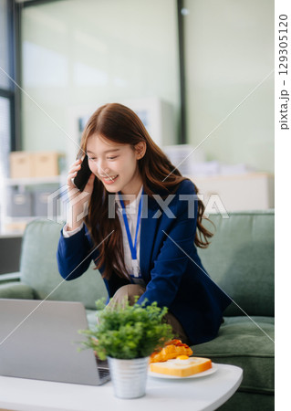 Businesswomen brainstorming in a cozy office, collaborating with a laptop and notebook Businesswomen brainstorming in a cozy office, collaborating with a laptop and notebook 129305120