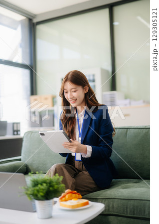 Asian businesswomen brainstorming in a cozy office, collaborating with a laptop and notebook. Perfect for teamwork Asian businesswomen brainstorming in a cozy office, collaborating with a laptop and notebook. Perfect for teamwork 129305121
