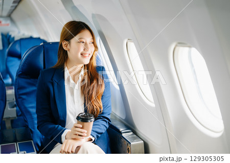 Young Asian executive excels in first class, multitasking with digital tablet, laptop and smartphone 129305305