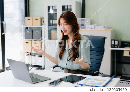 Confident Asian woman with a smile standing holding notepad and tablet 129305420