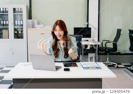 Asian business woman are delighted and happy with the work they do on their tablet, laptop and taking notes 129305479