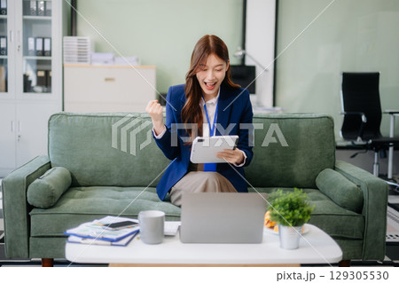 Young Asian working on laptops and tablets in a stylish office. Perfect for creativity, remote work, modern lifestyle, Young Asian working on laptops and tablets in a stylish office. Perfect for creativity, remote work, modern lifestyle, 129305530