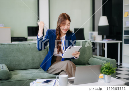 Young Asian working on laptops and tablets in a stylish office. Perfect for creativity, remote work, modern lifestyle, Young Asian working on laptops and tablets in a stylish office. Perfect for creativity, remote work, modern lifestyle, 129305531