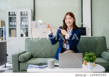 Asian businesswomen brainstorming in a cozy office, collaborating with a laptop and notebook. Perfect for teamwork 129305545