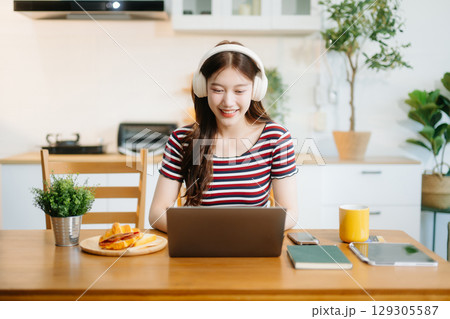 oung Asian woman with sitting working on laptops and tablets in a cozy workspace. Perfect for education, innovation, oung Asian woman with sitting working on laptops and tablets in a cozy workspace. Perfect for education, innovation, 129305587
