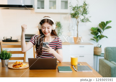 oung Asian woman with sitting working on laptops and tablets in a cozy workspace. Perfect for education, innovation, oung Asian woman with sitting working on laptops and tablets in a cozy workspace. Perfect for education, innovation, 129305591