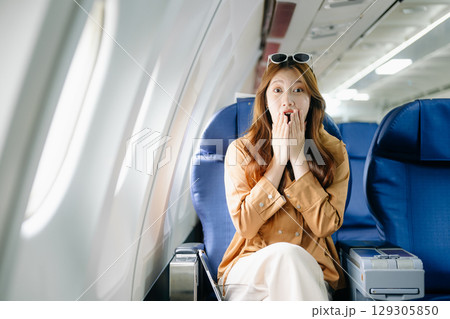 Smiling woman in first-class airplane seat, showcasing luxury, comfort, and elegance in travel. Smiling woman in first-class airplane seat, showcasing luxury, comfort, and elegance in travel. 129305850