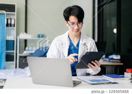 Doctor analyzing patient data on tablet in clinical lab. Medical professional in hospital with laptop, blood samples 129305888