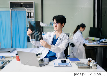 Doctor analyzing patient data on tablet in clinical lab. Medical professional in hospital with laptop, blood samples 129305890
