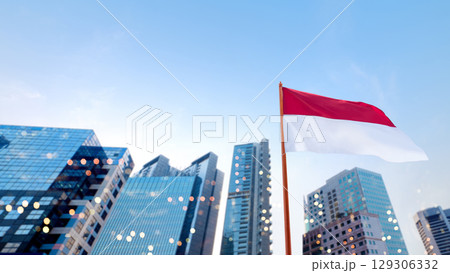 Closeup view of the Indonesian national flag waving with skyscrapers and a blue sky background. Celebrate Indonesia Independence Day. Concept of Kemerdekaan Indonesia Closeup view of the Indonesian national flag waving with skyscrapers and a blue sky background. Celebrate Indonesia Independence Day. Concept of Kemerdekaan Indonesia 129306332