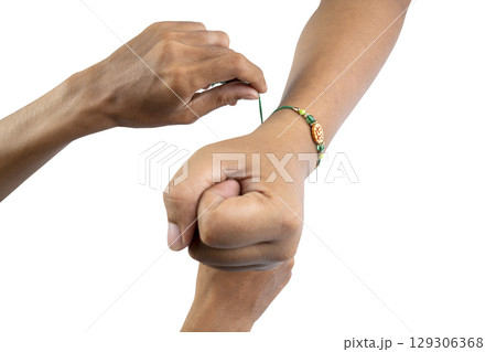 Human hands tying colorful rakhis on the wrist, isolated over a white background, celebrating the bond of love and protection. Concept of the Raksha Bandhan festival 129306368