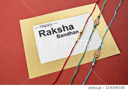 Closeup view of colorful rakhis with a message of Happy Raksha Bandhan on the paper with a colored background. Celebrating the bond of love and protection. Concept of the Raksha Bandhan festival Closeup view of colorful rakhis with a message of Happy Raksha Bandhan on the paper with a colored background. Celebrating the bond of love and protection. Concept of the Raksha Bandhan festival 129306380
