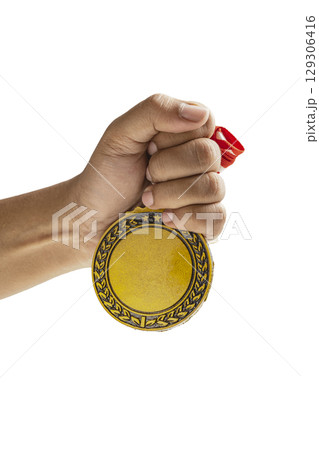 Human hand holding golden award medal suspended from a red and white striped ribbon isolated over a white background. Copy space. Symbol of achievement, recognition, or competition 129306416