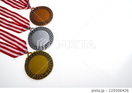 Set of the bronze, silver, and golden award medals suspended from a red and white striped ribbon isolated over a white background. Copy space. Symbol of achievement, recognition, or competition 129306426