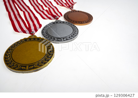Set of the bronze, silver, and golden award medals suspended from a red and white striped ribbon isolated over a white background. Copy space. Symbol of achievement, recognition, or competition Set of the bronze, silver, and golden award medals suspended from a red and white striped ribbon isolated over a white background. Copy space. Symbol of achievement, recognition, or competition 129306427