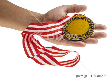 Human hand holding golden award medal suspended from a red and white striped ribbon isolated over a white background. Copy space. Symbol of achievement, recognition, or competition Human hand holding golden award medal suspended from a red and white striped ribbon isolated over a white background. Copy space. Symbol of achievement, recognition, or competition 129306432