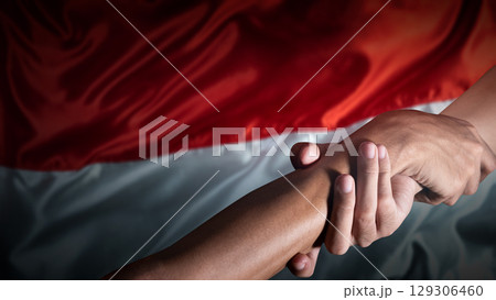 Human holding hands with an Indonesian national flag background. Celebrate Indonesia Independence Day. Concept of Kemerdekaan Indonesia 129306460