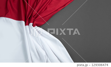 Closeup view of the Indonesian national flag with a black wall background. Copy space. Celebrate Indonesia Independence Day. Concept of Kemerdekaan Indonesia Closeup view of the Indonesian national flag with a black wall background. Copy space. Celebrate Indonesia Independence Day. Concept of Kemerdekaan Indonesia 129306474