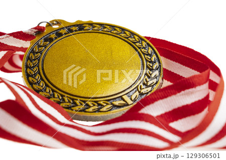 Closeup view of the golden award medal suspended from a red and white striped ribbon isolated over a white background. Copy space. Symbol of achievement, recognition, or competition 129306501