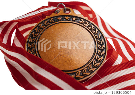 Closeup view of the bronze award medal suspended from a red and white striped ribbon isolated over a white background. Copy space. Symbol of achievement, recognition, or competition 129306504