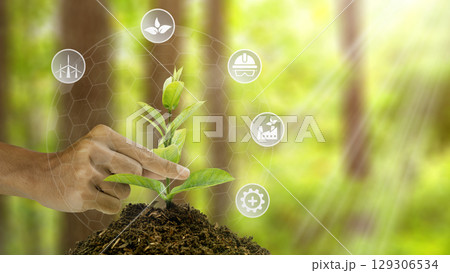 Human hand holding a plant on the ground with an industrial icon. Concept of World Engineer Day 129306534