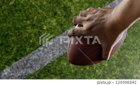 American football player holding the ball during the game in an American football stadium. Concept of sport American football player holding the ball during the game in an American football stadium. Concept of sport 129306842