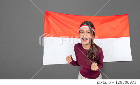 Indonesian southeast asian woman celebrating Indonesia Independence Day on the 17th of August with the Indonesian national flag. Concept of Kemerdekaan Indonesia 129306973