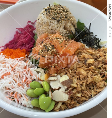 A vibrant poke bowl filled with fresh, marinated fish, rice, and colorful toppings like avocado, seaweed, and sesame seeds. A healthy, satisfying meal with rich textures and flavors. 129307394