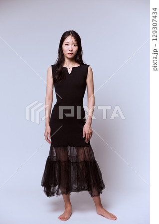 黒いドレスでポージングする女性モデルのスタジオポートレート 129307434