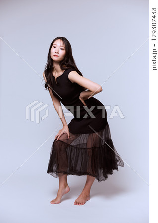 黒いドレスでポージングする女性モデルのスタジオポートレート 129307438