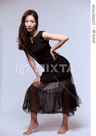 黒いドレスでポージングする女性モデルのスタジオポートレート 129307439