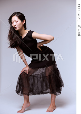 黒いドレスでポージングする女性モデルのスタジオポートレート 129307443