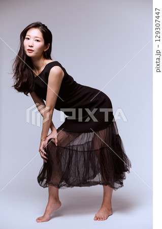 黒いドレスでポージングする女性モデルのスタジオポートレート 129307447