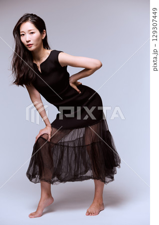 黒いドレスでポージングする女性モデルのスタジオポートレート 129307449