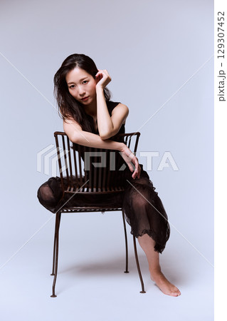 黒いドレスでポージングする女性モデルのスタジオポートレート 129307452