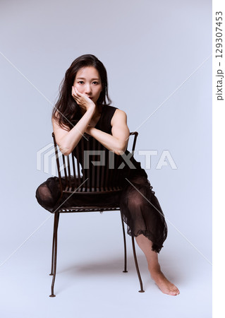 黒いドレスでポージングする女性モデルのスタジオポートレート 129307453