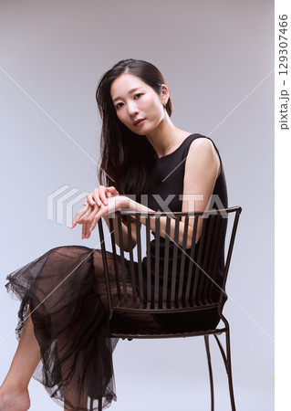 黒いドレスでポージングする女性モデルのスタジオポートレート 129307466