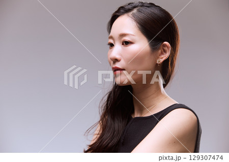 黒いドレスでポージングする女性モデルのスタジオポートレート 129307474
