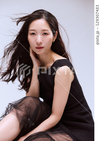黒いドレスでポージングする女性モデルのスタジオポートレート 129307483