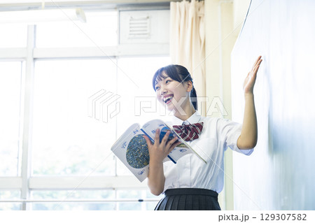 黒板の前で発表する女子高生 129307582
