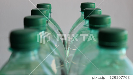 Two rows of plastic water bottles with focus on the last bottles isolated on white 129307768